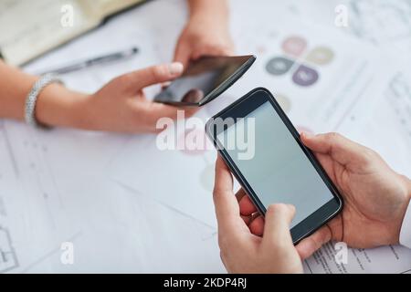 Deux hommes d'affaires utilisent leur téléphone portable à un bureau pour trouver les meilleurs outils pour leur travail. Banque D'Images