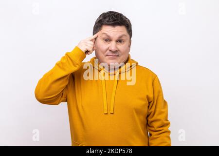 Portrait de l'homme montrant le geste stupide, regardant la caméra avec la condamnation et le blâme pour le plan aliéné, suggestion stupide, portant le sweat à capuche de style urbain. Studio d'intérieur isolé sur fond blanc. Banque D'Images