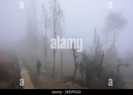 Srinagar, Inde. 07th novembre 2022. Un homme marche le long de la colline pendant un temps brumeux à la périphérie de Srinagar. Les pluies ont continué à frapiller les plaines tandis que les tronçons supérieurs ont reçu des chutes de neige alors que l'homme météorologique avait prédit un temps plus humide à Jammu-et-Cachemire jusqu'à 11 novembre. Crédit : SOPA Images Limited/Alamy Live News Banque D'Images