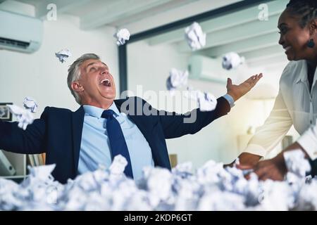 Cette équipe a trouvé la meilleure façon de gérer les formalités administratives : deux hommes d'affaires heureux qui lançaient en l'air de belles feuilles de papier froissé. Banque D'Images