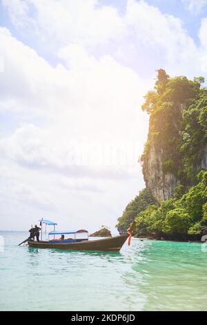 Un autre jour au paradis, un homme debout sur un bateau flottant dans les eaux tropicales. Banque D'Images