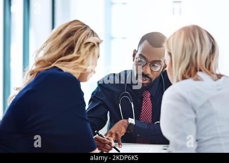 Voici vos options... un jeune couple ayant une consultation avec son médecin. Banque D'Images