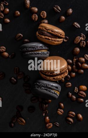 Dessert au macaron sucré avec des grains de café sur la table noire. Banque D'Images