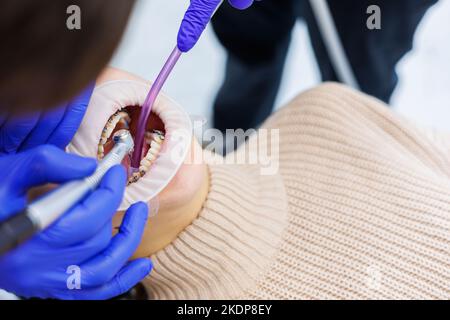 Les dents d'une femme avec des bretelles métalliques sont traitées à la clinique. Un orthodontiste utilise des instruments dentaires pour placer des bretelles sur les dents d'un patient. Sélection Banque D'Images