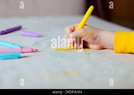 Le dessin à la main de l'enfant avec un stylo feutre jaune sur la sellerie grise du canapé. La vie quotidienne taches sales pour le lavage et le concept propre Banque D'Images