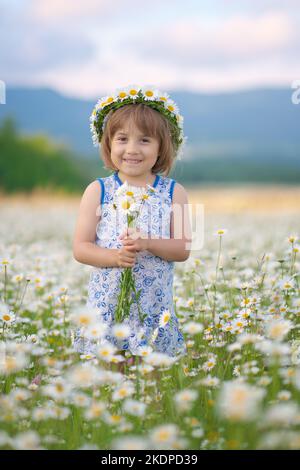 Petite fille mignonne dans un grand pré de camomille.Composition portrait. Banque D'Images