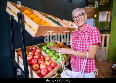 Femme mature achetant des produits dans la boutique de fruits et légumes. Banque D'Images