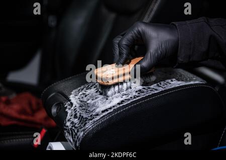 Les détails de voiture ou le travailleur de studio de lavage de voiture nettoie le cuir noir de la garniture de voiture Banque D'Images