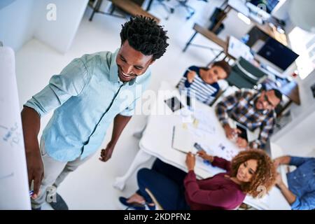 Je travaille ensemble sur des idées passionnantes. Un jeune designer donne une présentation à ses collègues dans un bureau. Banque D'Images