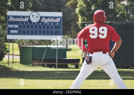 Un joueur de baseball sur le terrain debout avec son dos vers la caméra avec un tableau de bord vide en arrière-plan Banque D'Images