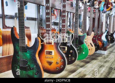 Une rangée de guitares électriques à corps plein accrochées à un présentoir dans une boutique de musique Banque D'Images