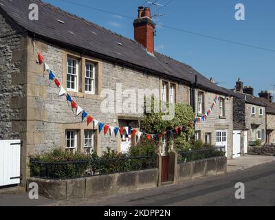 Rangée de cottages traditionnels en pierre, avec bunkting, dans le joli village d'Ashford dans l'eau, Peak District, Derbyshire, Royaume-Uni Banque D'Images