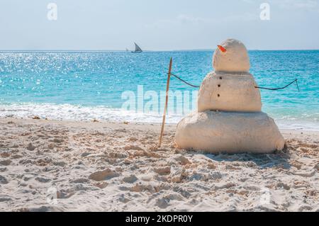 Fête du nouvel an sur la plage d'une île tropicale paradisiaque exotique avec un bonhomme de neige au sable et un lagon bleu d'eau sur l'océan, par une chaude journée ensoleillée Banque D'Images