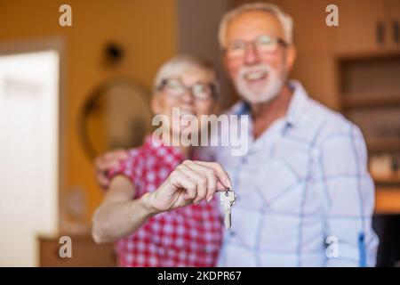 Portrait d'un couple senior heureux à la maison. Les aînés adoptent et tiennent la clé de leur nouvelle maison. Banque D'Images