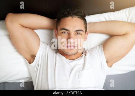 Il suffit de se reposer et de se détendre. Un beau jeune homme allongé dans le lit. Banque D'Images