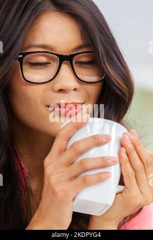 Belle jeune asiatique chinoise femme ou fille yeux fermés portant des lunettes ou des lunettes bonne odeur et boire une tasse ou une tasse de café Banque D'Images