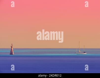 Longue exposition d'un bateau et d'une bouée sur l'eau turquoise bleu et le ciel orange le matin, caraïbes, vacances, lever du soleil, Wanderlust avec l'espace de copie Banque D'Images