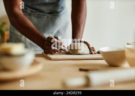 Gros plan d'un artiste masculin créant un bol en céramique fait main dans un confortable studio de poterie, un espace de copie Banque D'Images