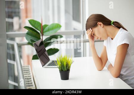 Jeune femme travaillant à l'office de bureau en face de l'ordinateur portable qui souffrent de maux chroniques quotidiennes Banque D'Images