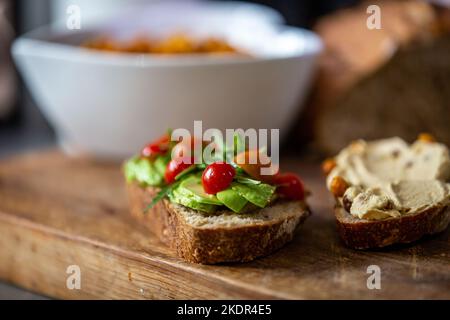 Gros plan de la fusée saine, de l'avocat, du houmous et de la tomate sur du pain au levain, avec une faible profondeur de champ Banque D'Images