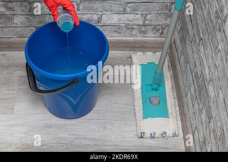 le détergent est versé du bouchon dans un seau d'eau. Photo de haute qualité. Banque D'Images