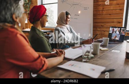 Des femmes entrepreneures heureuses assistent à une réunion en ligne avec leurs partenaires d'affaires. Groupe de femmes d'affaires multiculturelles ayant une vidéoconférence Banque D'Images