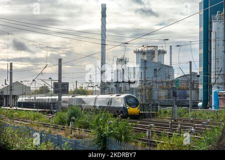 Train Avanti Pendolino à la gare de Warrington Bank Quay, en face de l'usine fermée de lever Faberge. Banque D'Images