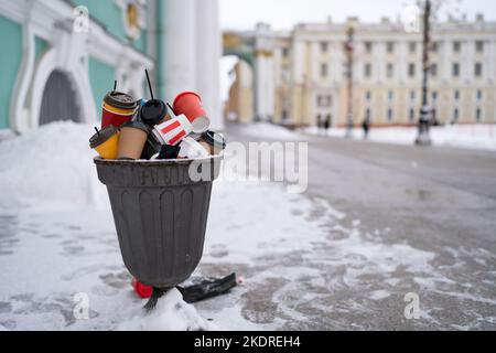 Poubelle surpeuplée dans la rue en hiver. Pile de gobelets jetables en plastique et en papier. Banque D'Images