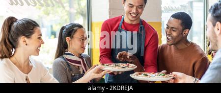 Bannière horizontale ou en-tête avec serveur servant de délicieuses pizzas margherita à des amis multiculturels dans le restaurant pizzeria confortable - amis multiethniques Banque D'Images