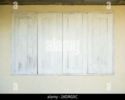 Les fenêtres en bois peintes en blanc sont fermées de la maison locale dans le village de campagne, vue de face pour l'arrière-plan. Banque D'Images