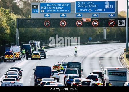 Thorpe, Royaume-Uni. 8th novembre 2022. Les agents de police de Surrey travaillent à retirer un activiste Just Stop Oil d'un portique suspendu au-dessus de l'autoroute M25 entre les jonctions 12 et 13. Il suffit de stopper le trafic sur plusieurs sites le M25 pour une deuxième journée dans le cadre de leur campagne visant à exiger que le gouvernement arrête tous les nouveaux permis et consentements de pétrole et de gaz. Crédit : Mark Kerrison/Alamy Live News Banque D'Images