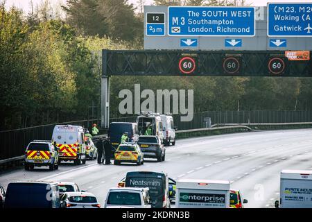 Thorpe, Royaume-Uni. 8th novembre 2022. Les policiers de Surrey (sur le portique) travaillent à retirer un activiste Just Stop Oil d'un portique suspendu au-dessus de l'autoroute M25 entre les jonctions 12 et 13. Il suffit de stopper le trafic sur plusieurs sites le M25 pour une deuxième journée dans le cadre de leur campagne visant à exiger que le gouvernement arrête tous les nouveaux permis et consentements de pétrole et de gaz. Crédit : Mark Kerrison/Alamy Live News Banque D'Images