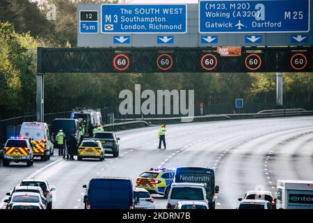 Thorpe, Royaume-Uni. 8th novembre 2022. Les agents de police de Surrey travaillent à retirer un activiste Just Stop Oil d'un portique suspendu au-dessus de l'autoroute M25 entre les jonctions 12 et 13. Il suffit de stopper le trafic sur plusieurs sites le M25 pour une deuxième journée dans le cadre de leur campagne visant à exiger que le gouvernement arrête tous les nouveaux permis et consentements de pétrole et de gaz. Crédit : Mark Kerrison/Alamy Live News Banque D'Images