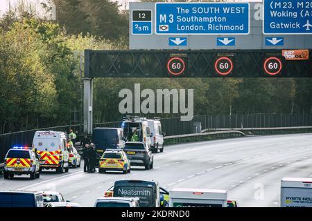 Thorpe, Royaume-Uni. 8th novembre 2022. Les policiers de Surrey (sur le portique) travaillent à retirer un activiste Just Stop Oil d'un portique suspendu au-dessus de l'autoroute M25 entre les jonctions 12 et 13. Il suffit de stopper le trafic sur plusieurs sites le M25 pour une deuxième journée dans le cadre de leur campagne visant à exiger que le gouvernement arrête tous les nouveaux permis et consentements de pétrole et de gaz. Crédit : Mark Kerrison/Alamy Live News Banque D'Images
