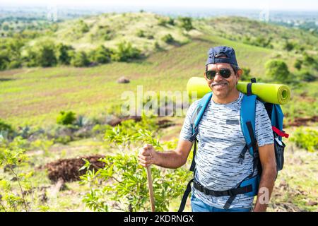 Portrait de randonneur d'âge moyen souriant avec sac à dos escalade montagne en regardant l'appareil photo - concept de confiance, trekking et la liberté Banque D'Images