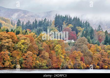 Pitlochry Perthshire Écosse Loch Faskally petite maison entourée d'une myriade de couleurs d'arbres en automne Banque D'Images