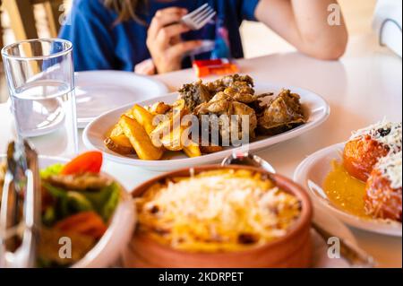 Cuisine traditionnelle grecque en famille dans la taverne du restaurant en Grèce. Sert de la cuisine grecque traditionnelle dans une taverne grecque sur des tables de dîner authentiques et Banque D'Images