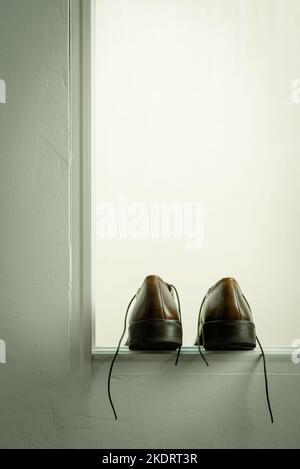 Chaussures d'homme en cuir marron dans la fenêtre ouverte Banque D'Images