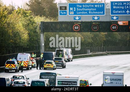 Thorpe, Royaume-Uni. 8th novembre 2022. Les policiers de Surrey retirent un activiste Just Stop Oil d'un portique suspendu au-dessus de l'autoroute M25 entre les jonctions 12 et 13. Il suffit de stopper le trafic sur plusieurs sites le M25 pour une deuxième journée dans le cadre de leur campagne visant à exiger que le gouvernement arrête tous les nouveaux permis et consentements de pétrole et de gaz. Crédit : Mark Kerrison/Alamy Live News Banque D'Images