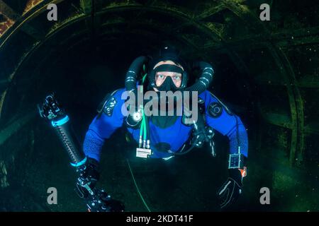 Plongée sous-marine avec remaération, combinaison sèche et caméra nageant à travers un tunnel sous-marin Banque D'Images