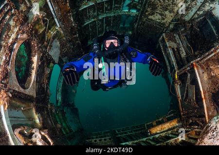 Plongée plongeur sur un circuit fermé resreniflard nager à travers l'épave d'un ancien avion sous l'eau Banque D'Images