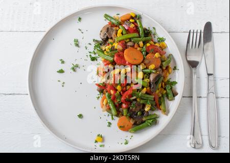 Légumes cuits sur une assiette pour plat de côté sain isolé sur fond blanc par le dessus Banque D'Images