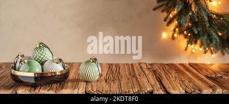 Décoration de Noël pastel, boules dans un bol noir sur une table en bois et couronne sur le mur Banque D'Images