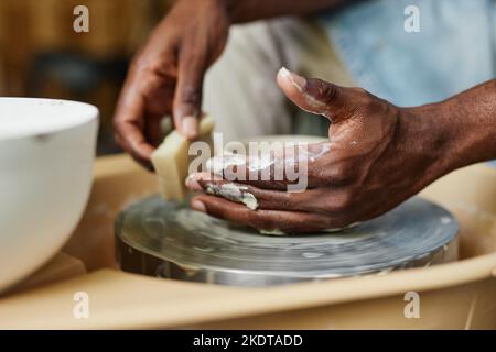 Gros plan des mains masculines en utilisant la roue de poterie et en créant des céramiques faites à la main en classe d'art Banque D'Images