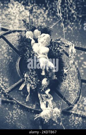 Couronne de Noël ou de l'Avent avec décoration Ange accrochée sur la porte. Photo rétro dans les tons sombres. Banque D'Images