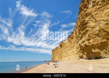 Personnes se détendant sur Hive Beach, adossé à des falaises de grès avec queue de Mare cirrus nuages au-dessus, Burton Bradstock, Dorset, Royaume-Uni, juillet. Banque D'Images