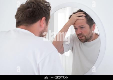 Un homme caucasien mature fatigué regarde le miroir. Banque D'Images