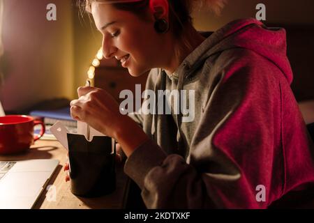 Fille blanche utilisant un ordinateur portable et manger de la nourriture asiatique tout en étant assis au bureau à la maison Banque D'Images