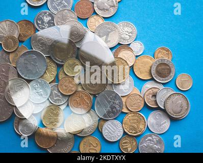 Explorer la collection de pièces de monnaie avec une loupe. Différentes devises internationales sous loupe, mise au point sélective Banque D'Images