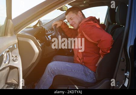 Un conducteur fatigué se tient sur son dos, ce qui lui fait mal après un long trajet. Concept de sécurité. Banque D'Images